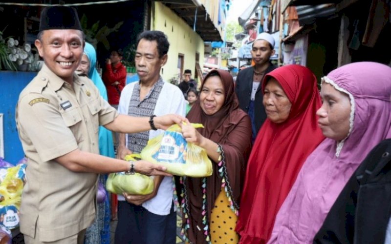 BERBAGI. Pejabat Fungsional Diskominfo Kota Makassar, Rahmat, membagikan paket sembako kepada warga di Lorong Wisata, Selasa (11/4/2023). foto: istimewa