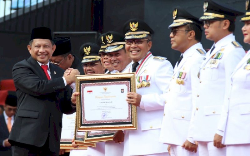 PENGHARGAAN. Menteri Dalam Negeri Tito Karnavian menyerahkan penghargaan kepada Wali Kota Makassar Moh Ramdhan Pomanto dalam Upacara Peringatan Hari Otonomi Daerah XXVII di Anjungan Pantai Losari Makassar, Sabtu (29/4/2023). foto: istimewa