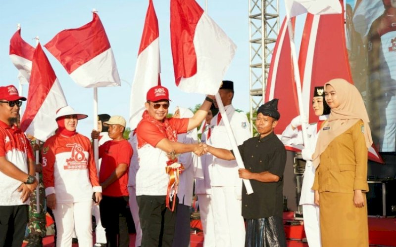 PENYERAHAN. Mendagri RI, Tito Karnavian, secara simbolis menyerahkan bendera pada acara puncak Gerakan Nasional Pembagian 10 Juta Bendera Merah Putih di Lapangan Hitam Pantai Bira Bulukumba, Jumat (11/8/2023). foto: istimewa