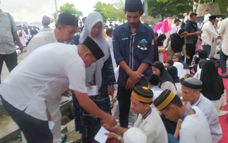 SANTUNAN. Camat Kepulauan Sangkarrang, Andi Asdhar, menyerahkan santunan di sela-sela buka puasa bersama anak yatim dan kaum duafa di Pantai Losari Makassar, Jumat (29/3/2024). foto: istimewa