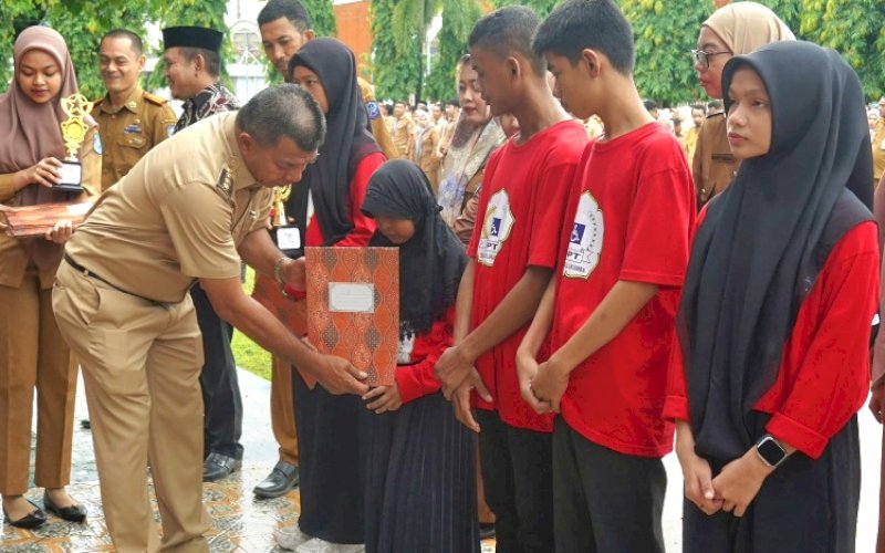 PENYERAHAN. Bupati Bulukumba, Andi Muchtar Ali Yusuf, menyerahkan piala dan sertifikat penghargaan kepada Siswa SLBN Bulukumba meraih juara umum pada FLS2N yang diselenggarakan MKKS SLB Wilayah VI di sela-sela Apel Gabungan Pemkab Bulukumba, Senin (29/4/2024). foto: istimewa