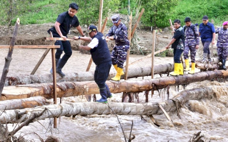 PERJUANGAN. Pj Gubernur Sulsel, Bahtiar Baharuddin, berjuang melewati titian bambu yang difungsikan sebagai jembatan darurat di tengah arus sungai yang sangat deras saat menemui warga terdampak banjir dan tanah longsor yang terisolir di Kecamatan Latimojong, Kabupaten Luwu, Kamis (9/5/2024). foto: istimewa