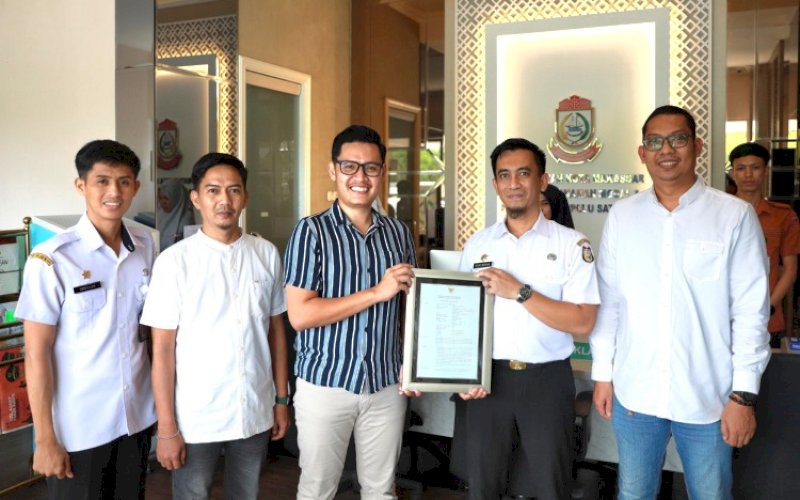 PENYERAHAN. Kepala Dinas Penanaman Modal dan Pelayanan Terpadu Satu Pintu (DPMPTSP) Kota Makassar, Helmy Budiman, menyerahkan Persetujuan Bangunan Gedung (PBG) rumah tinggal kepada Andika Priyatno sebagai pemohon di Kantor DPMPTSP Kota Makassar, Mal GTC Makassar, Rabu (22/5/2024). foto: istimewa