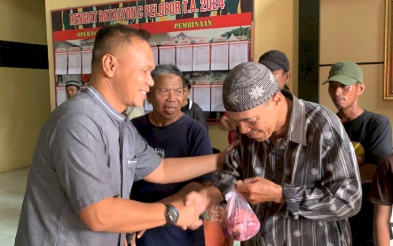 PENYERAHAN. Komandan Batalyon (Danyon) C Pelopor Satbrimob Polda Sulsel, Kompol Nur Ichsan, menyerahkan daging kurban kepada warga di Mako Batalyon C Pelopor Satbrimob Polda Sulsel, Kabupaten Bone, Senin (17/6/2024). foto: istimewa