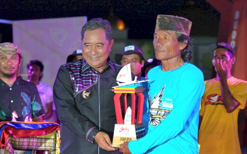 JUARA. Pj Gubernur Sulbar, Bahtiar Baharuddin, menyerahkan piala kepada juara Sandeq Heritage Festival 2024 pada Malam Ramah Tamah Hari Jadi/Hari Ulang Tahun (HUT) Provinsi Sulbar ke-20 di Anjungan Pantai Manakarra Kabupaten Mamuju, Provinsi Subar, Minggu (22/9/2024). foto: istimewa
