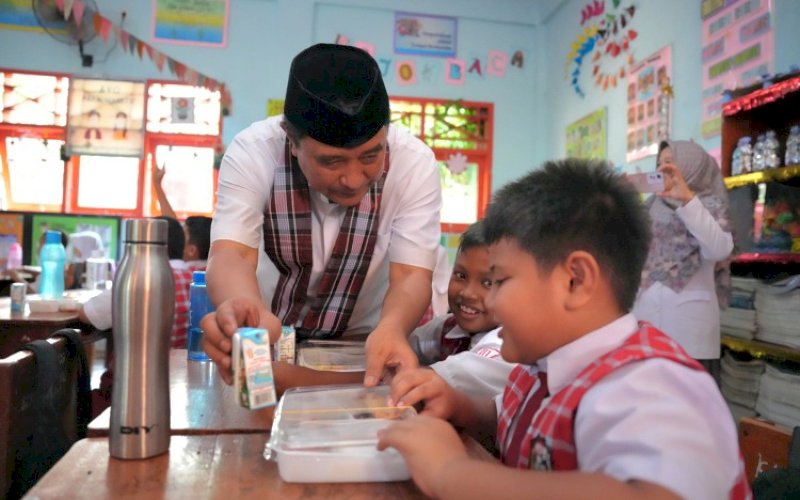 UJI COBA. Pj Gubernur Sulbar, Bahtiar Baharuddin, menyerahkan paket makan kepada salah seorang siswa saat meninjau uji coba makan bergizi gratis di SDN 2 Kampung Baru Majene, Sulbar, Rabu (30/10/2024). foto: istimewa