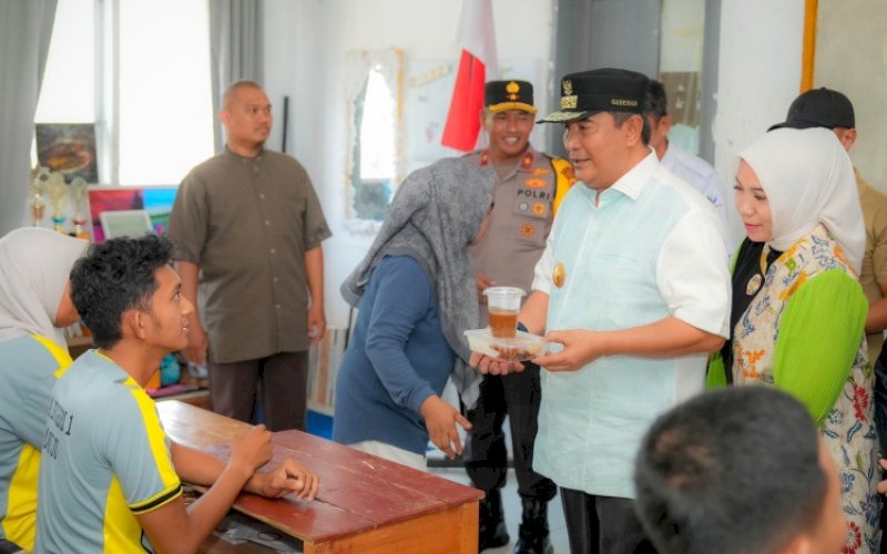PENYERAHAN. Pj Gubernur Sulbar, Bahtiar Baharuddin, secara simbolis menyerahkan makanan kepada salah seorang siswa saat melihat langsung penerapan makan gratis di SMAN 1 Mamuju, Jumat (25/10/2024). foto: istimewa