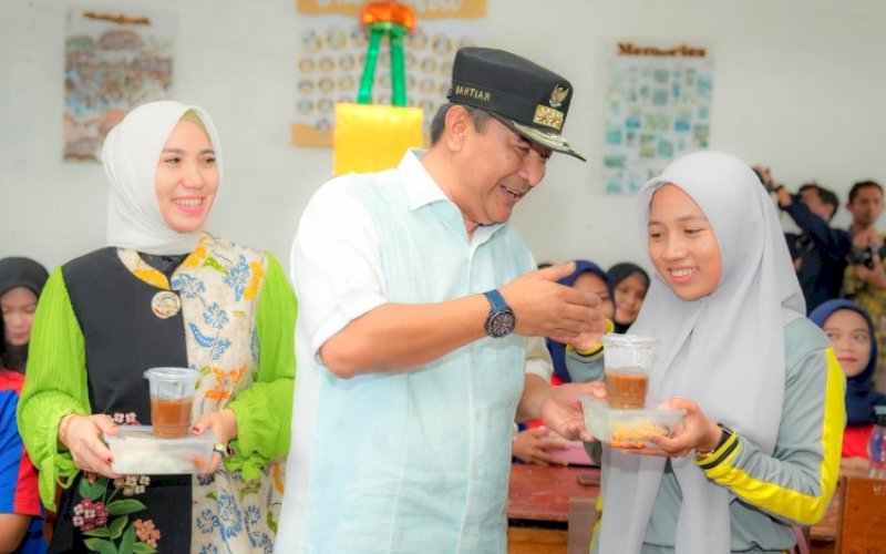 PENYERAHAN. Pj Gubernur Sulbar, Bahtiar Baharuddin, secara simbolis menyerahkan makanan kepada salah seorang siswa saat melihat langsung penerapan makan gratis di SMAN 1 Mamuju, Jumat (25/10/2024). foto: istimewa