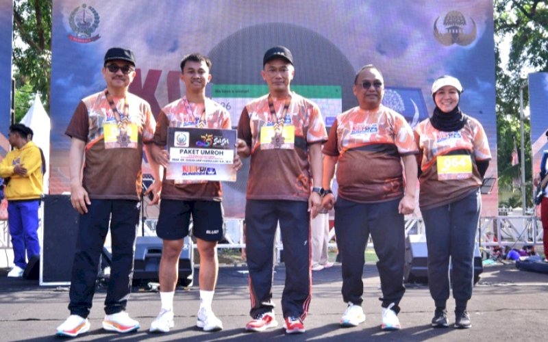 PEMENANG. Pj Gubernur Sulsel, Zudan Arif Fakrulloh, menyerahkan hadiah umrah kepada peserta Korpri Run 2024, Azhar Ismail, usai mengikuti lari 10K dan 5K, Minggu (27/10/2024). foto: istimewa