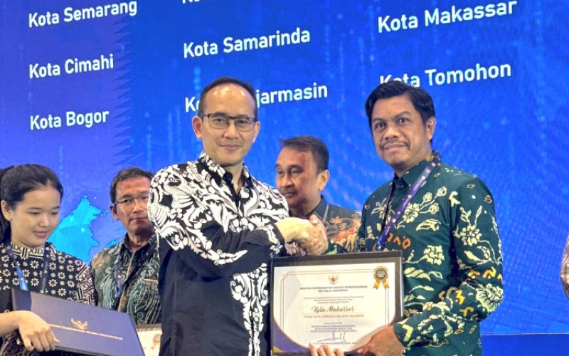 PENGHARGAAN TP2DD. Asisten Deputi Perekonomian Daerah dan Sektor Riil Kementerian Koordinator Bidang Perekonomian Puji G menyerahkan penghargaan TP2DD Kota Terbaik kepada Kepala Bapenda Kota Makassar Firman Hamid Pagarra di Dyandra Convention Center Surabaya, Jatim, Kamis (7/11/2024). foto: istimewa