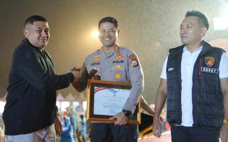 PENGHARGAAN. Wali Kota Makassar Munafri Arifuddin menyerahkan penghargaan kepada Kapolrestabes Makassar Kombes Pol Arya Perdana bersama tim Jatanras Polrestabes Makassar pada puncak perayaan HUT Kota Makassar ke-418 di Lapangan Karebosi Makassar, Minggu (9/11/2025) malam. foto: istimewa