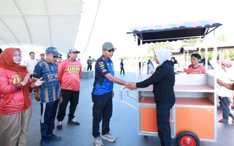 BANTUAN. Bupati Bulukumba, Andi Muchtar Ali Yusuf, secara simbolis menyerahkan bantuan gerobak kepada pelaku UMKM di pelataran panggung Pantai Merpati Bulukumba, Jumat (24/4/2026). foto: istimewa