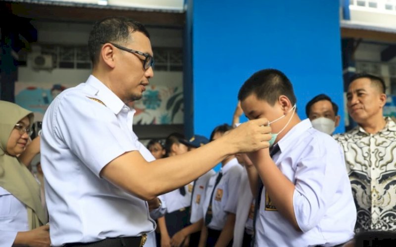 MEMAKAI MASKER. Sekda Kota Makassar, Andi Zulkifly Nanda, memasangkan masker ke salah satu siswa saat turun ke sekolah membagikan masker sebagai bentuk kepedulian atas dampak kabut asap yang kian memburuk menyelimuti langit Kota Makassar, Rabu (14/10/2026). foto: istimewa